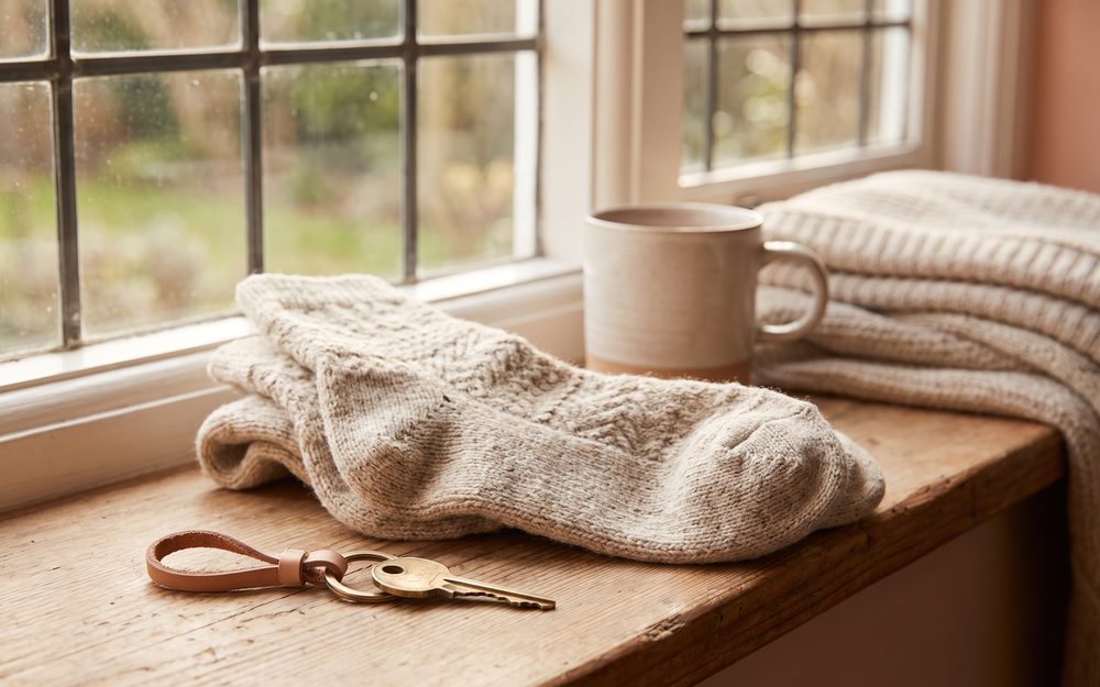 Hausschlüssel und Wollsocken auf einer warmen Fensterbank